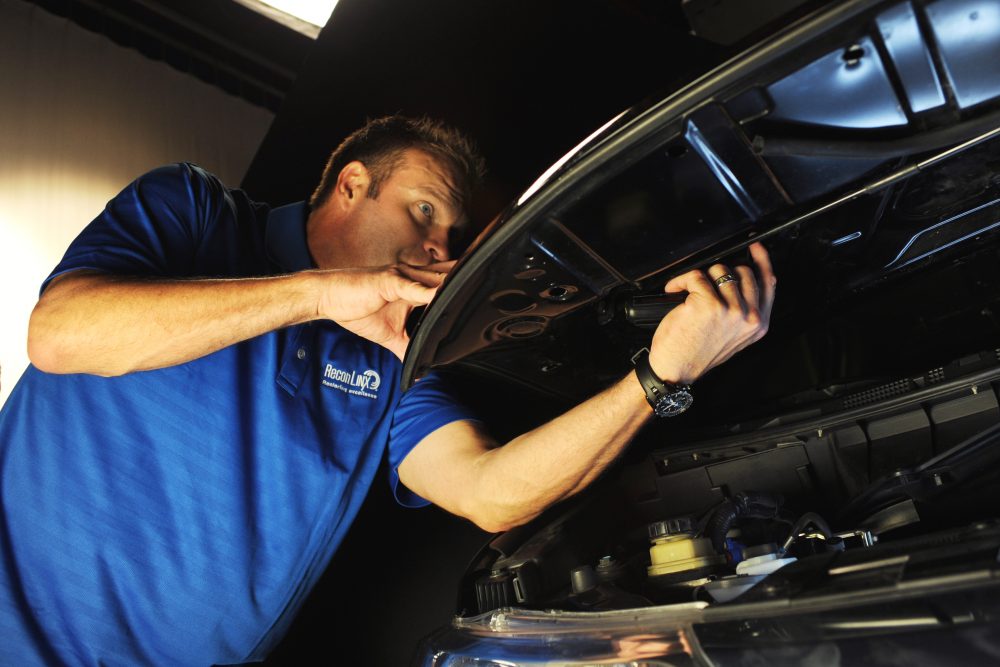 A certified repair technician repairs a dent with a specialized tool